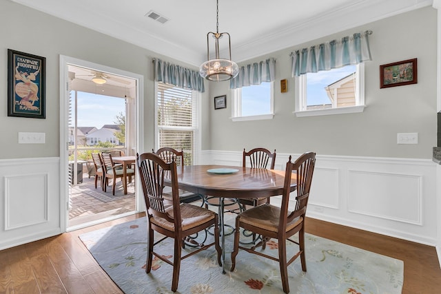 dining room featuring visible vents, crown molding, a wainscoted wall, and wood finished floors