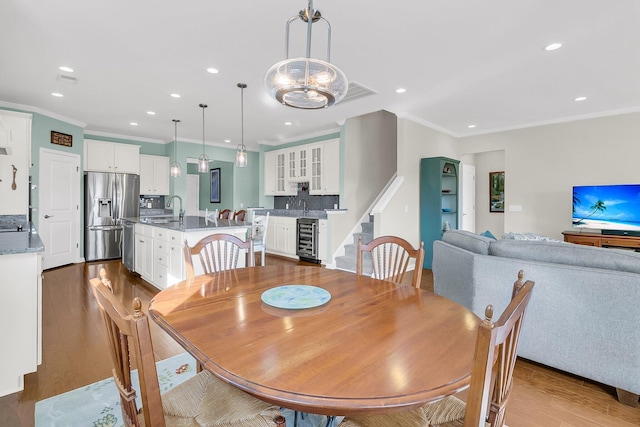 dining area featuring crown molding, wine cooler, recessed lighting, and wood finished floors