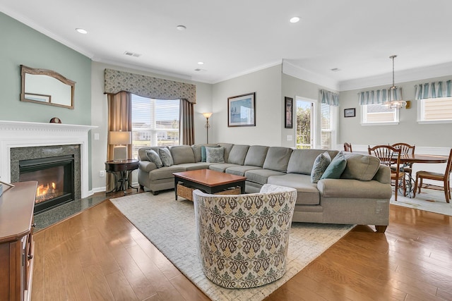 living room featuring visible vents, a healthy amount of sunlight, ornamental molding, and wood-type flooring