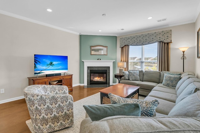 living room with visible vents, wood finished floors, a fireplace, crown molding, and baseboards