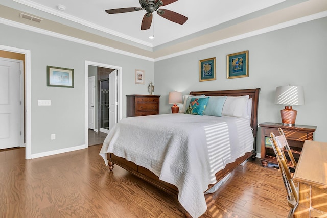 bedroom featuring visible vents, baseboards, wood finished floors, and crown molding