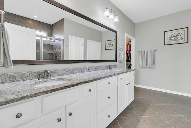 bathroom featuring baseboards, double vanity, a stall shower, a sink, and tile patterned floors