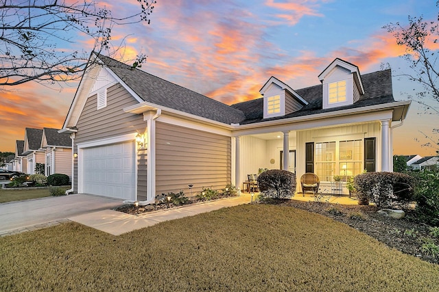 view of front of property featuring a garage, a front lawn, driveway, and a shingled roof