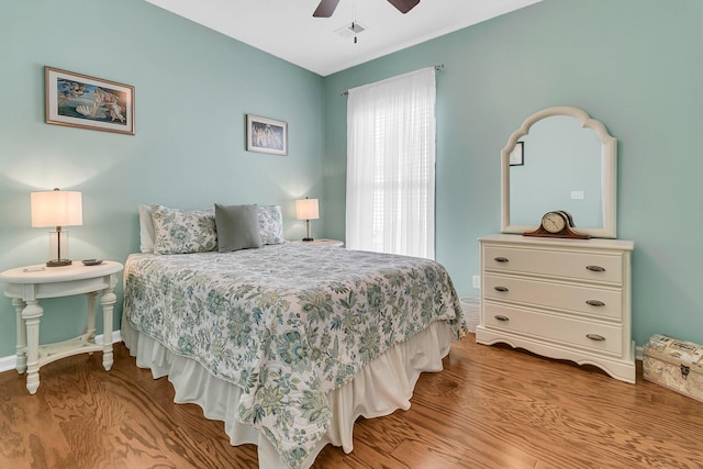 bedroom with a ceiling fan, wood finished floors, visible vents, and baseboards