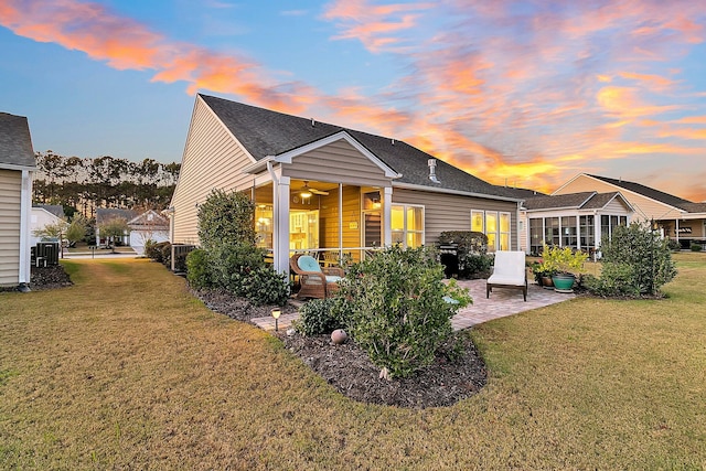 rear view of property featuring a yard, a shingled roof, ceiling fan, and a patio area