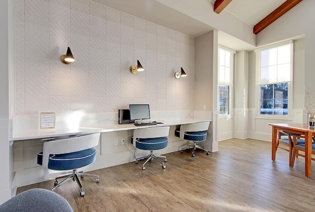 office space featuring wood finished floors, vaulted ceiling with beams, and built in study area