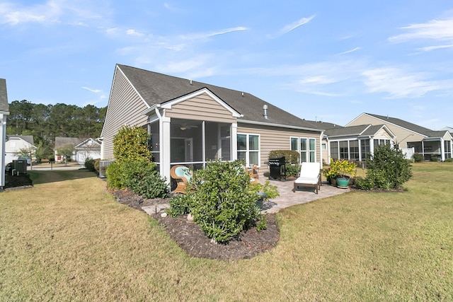 back of property with a patio, a lawn, a shingled roof, and a sunroom