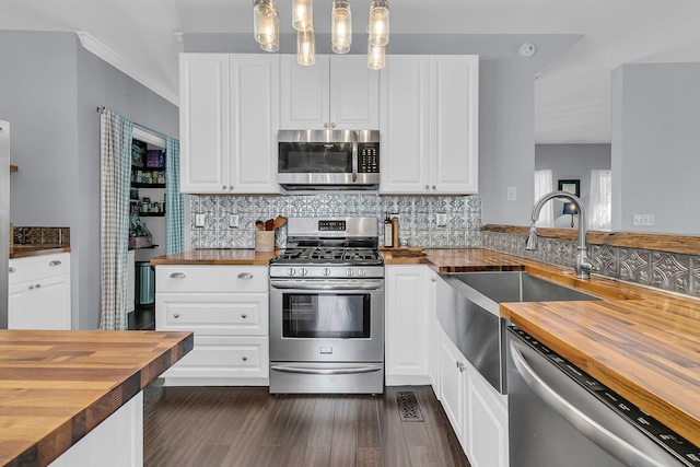 kitchen featuring stainless steel appliances, white cabinetry, wooden counters, and decorative light fixtures