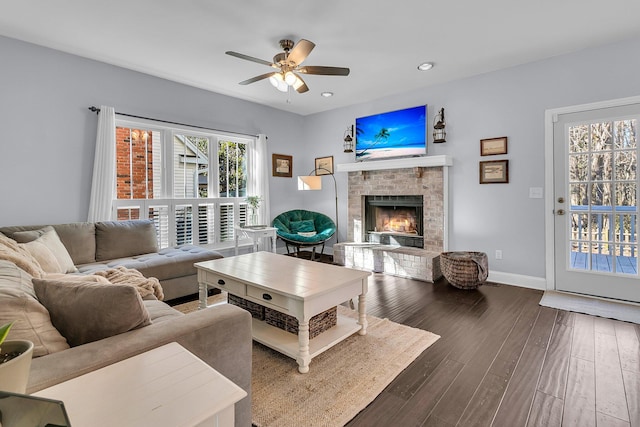 living room featuring ceiling fan, dark hardwood / wood-style floors, and a fireplace