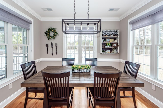 dining room with ornamental molding, baseboards, visible vents, and light wood finished floors