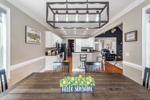 dining space with crown molding, baseboards, and wood finished floors