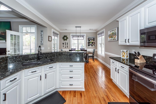 kitchen with range with electric cooktop, stainless steel microwave, ornamental molding, light wood-style floors, and a sink