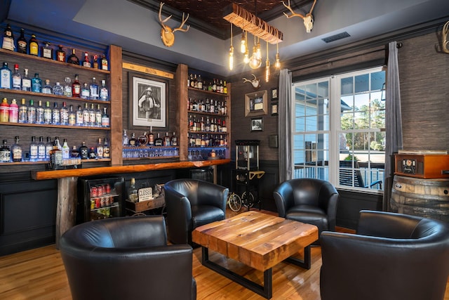 bar with a dry bar, wood finished floors, and visible vents