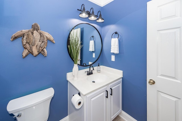 half bathroom featuring toilet, baseboards, and vanity