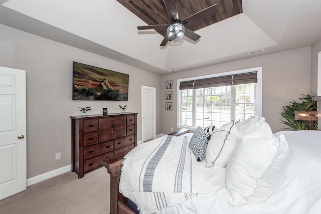 bedroom featuring light carpet, baseboards, visible vents, a ceiling fan, and a tray ceiling