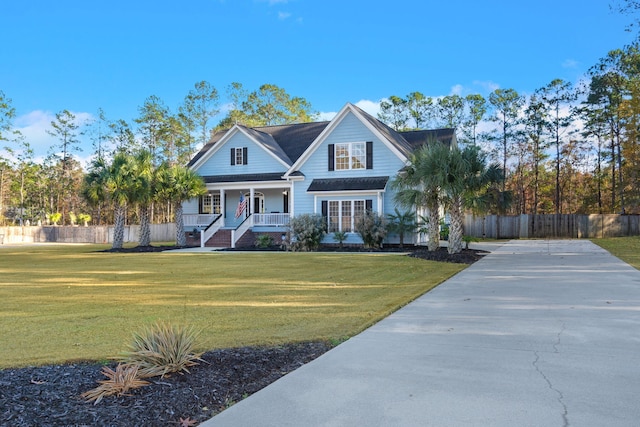 view of front of property with covered porch, fence, and a front lawn