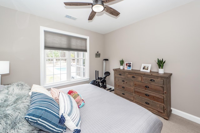 bedroom with light carpet, ceiling fan, visible vents, and baseboards