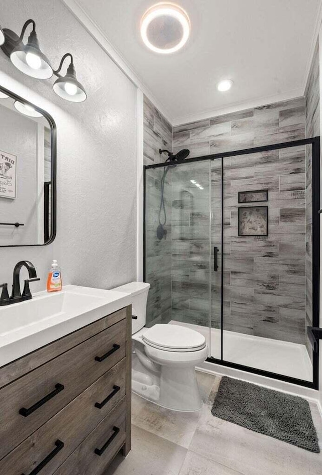 bathroom featuring toilet, a stall shower, ornamental molding, and vanity