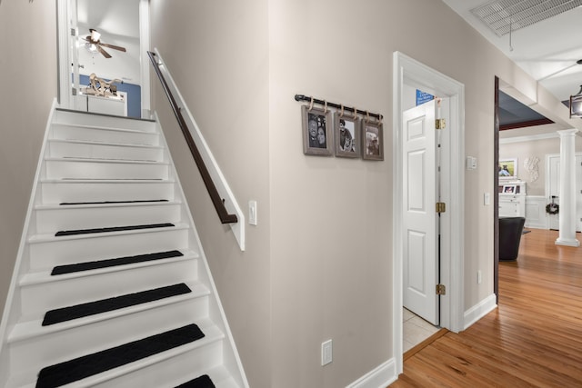 stairs with ceiling fan, visible vents, decorative columns, and wood finished floors