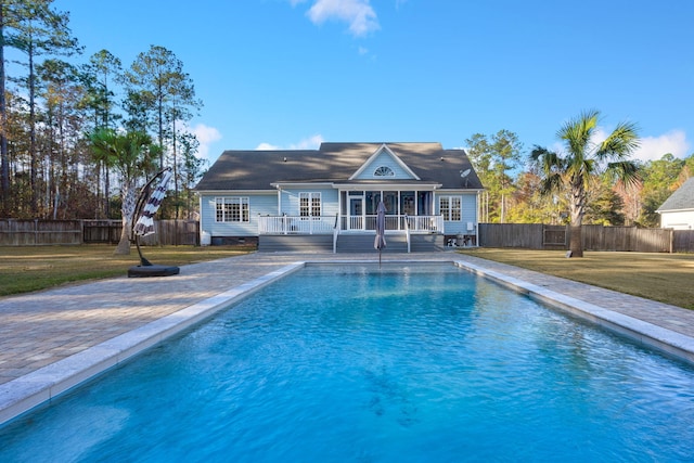 back of property with a deck, a lawn, a fenced backyard, and a fenced in pool