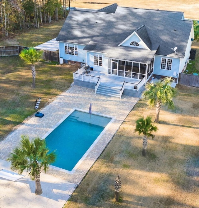 back of house featuring a deck, a fenced backyard, a sunroom, a yard, and a fenced in pool