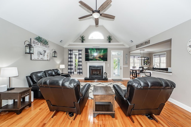 living area featuring visible vents, baseboards, a fireplace with raised hearth, ceiling fan, and light wood-style floors