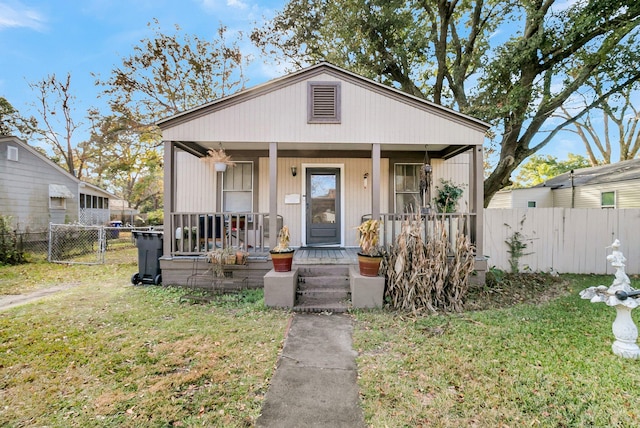 bungalow featuring covered porch and a front yard