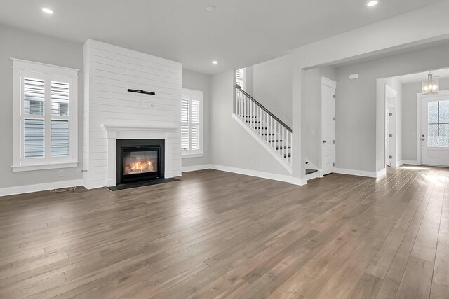 unfurnished living room featuring a chandelier and dark hardwood / wood-style floors