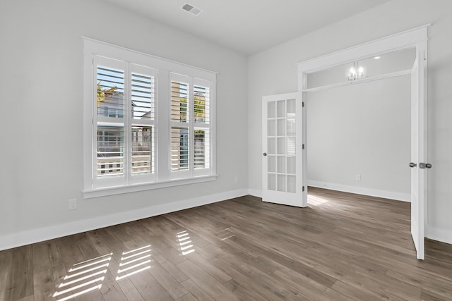 unfurnished room with dark hardwood / wood-style flooring, french doors, and a notable chandelier