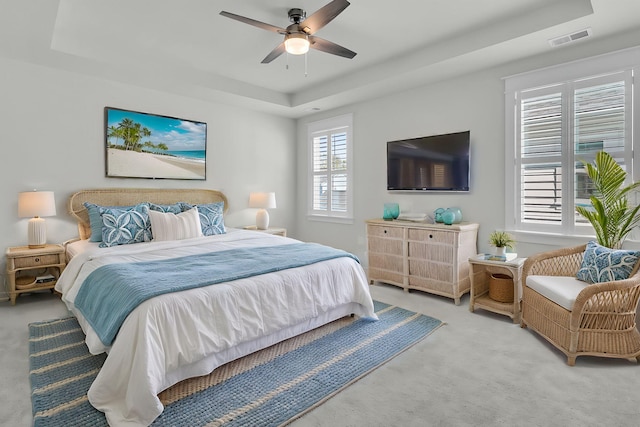 carpeted bedroom with a tray ceiling and ceiling fan