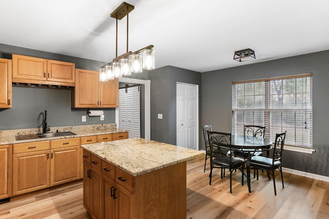 kitchen with pendant lighting, sink, light hardwood / wood-style floors, and a center island