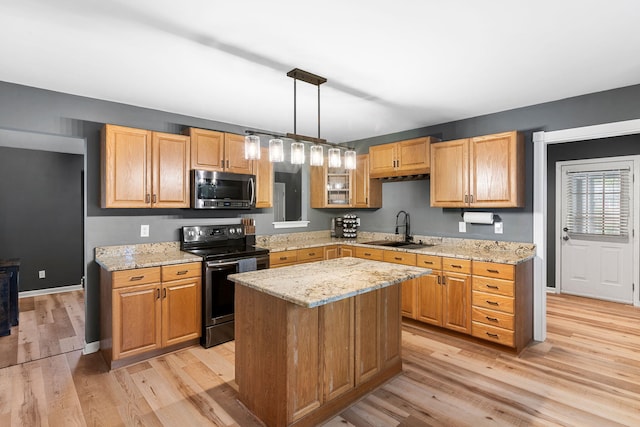 kitchen with a center island, stainless steel appliances, decorative light fixtures, sink, and light hardwood / wood-style flooring