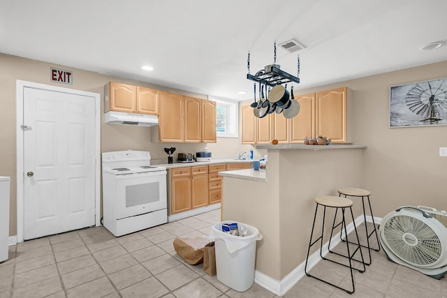 kitchen featuring light tile patterned floors, sink, a breakfast bar area, white electric range oven, and light brown cabinets