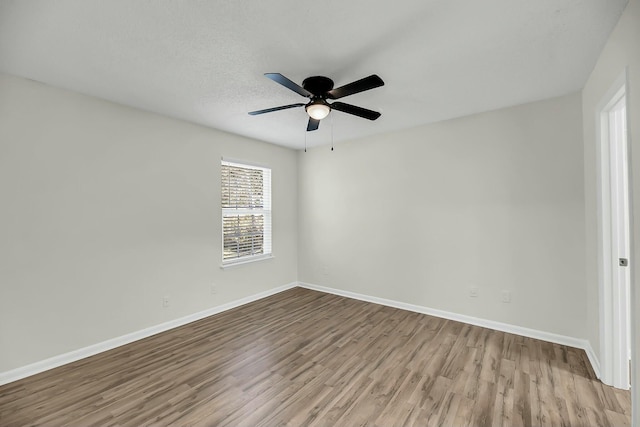 empty room with a ceiling fan, a textured ceiling, baseboards, and wood finished floors