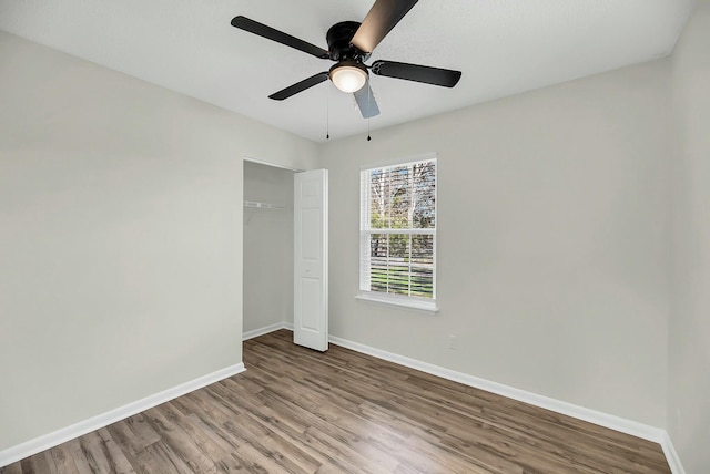 unfurnished bedroom with ceiling fan, a closet, baseboards, and wood finished floors