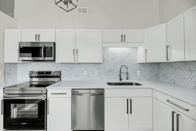 kitchen featuring appliances with stainless steel finishes, light countertops, a sink, and decorative backsplash