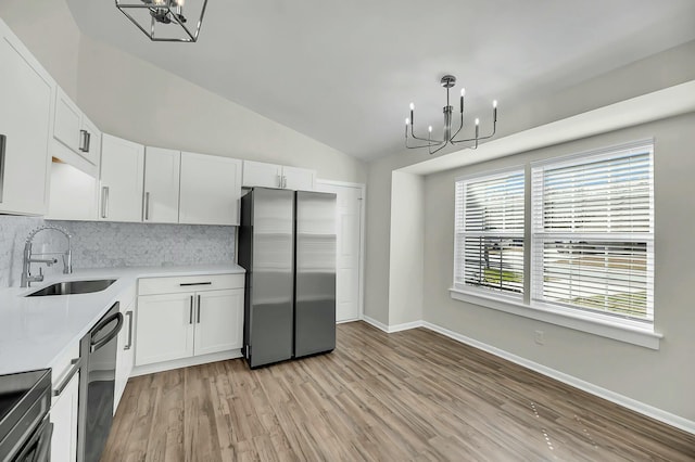 kitchen with dishwasher, a sink, freestanding refrigerator, and an inviting chandelier