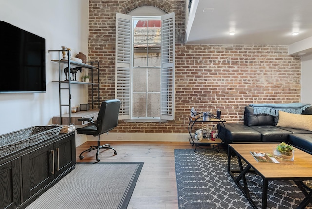 office with light wood-style floors, brick wall, and baseboards