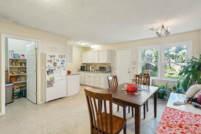 dining area with a chandelier, a toaster, a textured ceiling, and light floors