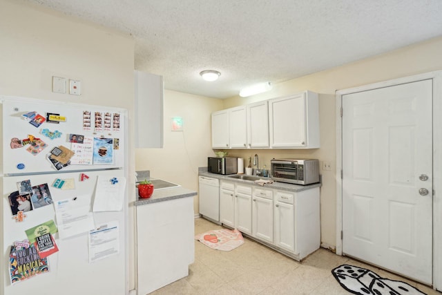 kitchen featuring a textured ceiling, white appliances, a sink, white cabinets, and light floors