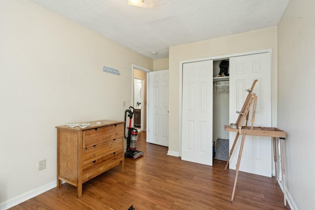 bedroom featuring dark wood-style floors, a closet, a textured ceiling, and baseboards