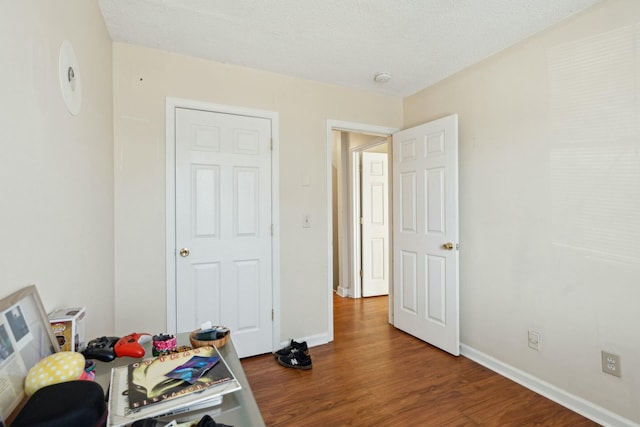 bedroom featuring a textured ceiling, baseboards, and wood finished floors