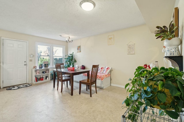 dining area with a chandelier, baseboards, a textured ceiling, and light floors