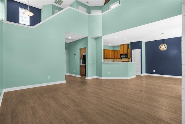 unfurnished living room with hardwood / wood-style floors, a high ceiling, and an inviting chandelier