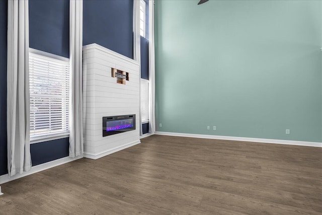 unfurnished living room with a fireplace, plenty of natural light, and dark wood-type flooring