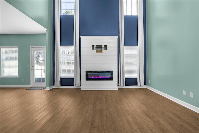 unfurnished living room featuring hardwood / wood-style floors, a large fireplace, and a wealth of natural light