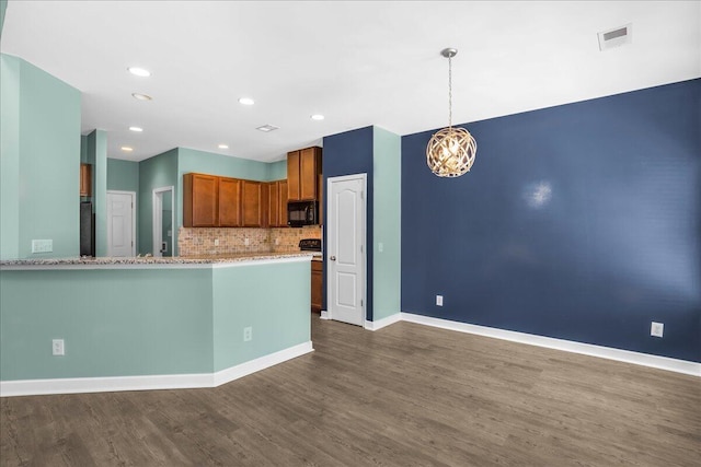 kitchen featuring hanging light fixtures, dark wood-type flooring, light stone counters, kitchen peninsula, and decorative backsplash