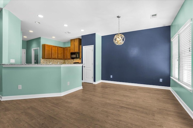 kitchen with hanging light fixtures, tasteful backsplash, dark hardwood / wood-style floors, kitchen peninsula, and a chandelier