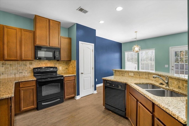 kitchen featuring decorative backsplash, sink, black appliances, decorative light fixtures, and light hardwood / wood-style floors