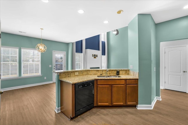 kitchen featuring light wood-type flooring, light stone counters, sink, pendant lighting, and black dishwasher